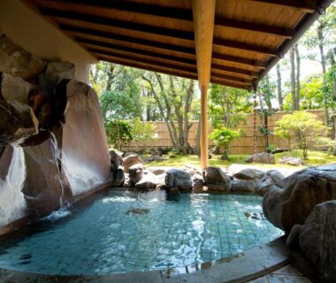 Tiled onsen pool under wooden roof with rock features at ABBA Resorts Izu Zagyosoh Shizuoka