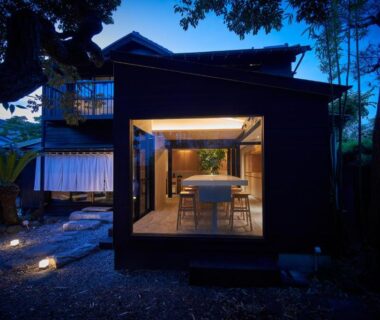 Evening view of lit exterior with open wooden dining room and garden pathway at AKAMA Kamakura Kanagawa