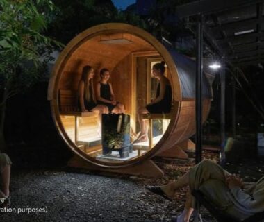 Barrel-shaped wooden outdoor seating pod lit at night with guests at AKAMA Kamakura Kanagawa