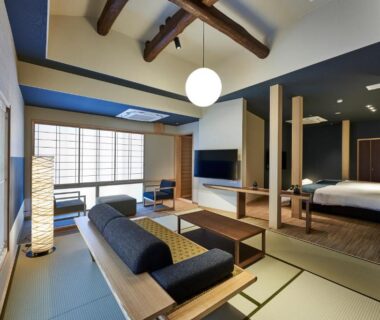 Tatami lounge with low table, sofa, shoji screens, exposed beams and bed at AKARI et KAORI, Shizuoka Chūbu