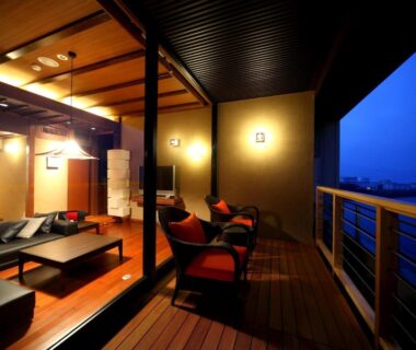 Evening wooden deck with chairs and open lounge connecting to indoor low tables at AMANE resort SEIKAI, Ōita