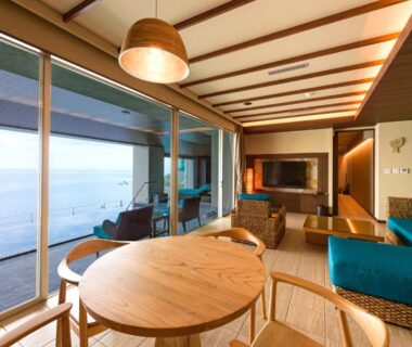 Round wooden dining table, low seating and floor-to-ceiling windows with sea view at AMANE resort SEIKAI in Ōita