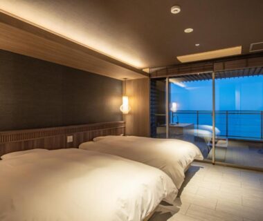 Two beds in modern Japanese room with balcony overlooking the sea at AMANE resort SEIKAI, Ōita