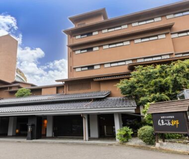 Multi-story hotel exterior with covered entrance, signboard and greenery at APA Hotel Kaga Katayamazu Onsen Kasuikyo in Ishikawa