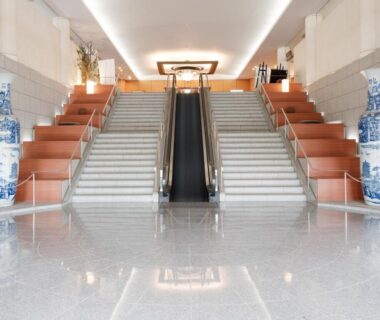 Polished stone lobby with central escalator, twin staircases and large porcelain vases at APA Hotel Kaga, Ishikawa