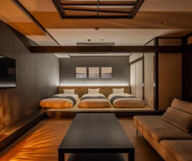 Modern Japanese-style room with low beds, shoji screens, wooden flooring and seating at AWA Nishi-Izu in Shizuoka
