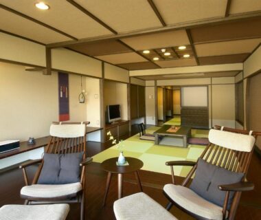 Spacious tatami room with low table and lounge chairs at Aburaya Tousen, Nagano