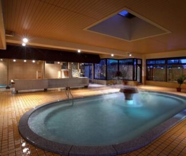 Spacious tiled indoor onsen pool with warm lighting at Aishinkan in Iwate, Tohoku, Japan