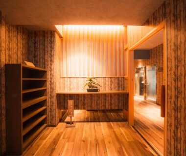 Wooden entrance foyer with shoe shelves and soft lighting at Shosuke no Yado Takinoyu, Fukushima