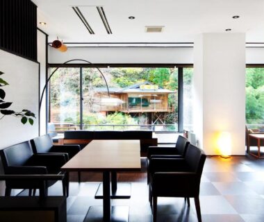Modern lounge with tables and chairs and large window overlooking garden at Shosuke no Yado Takinoyu, Fukushima