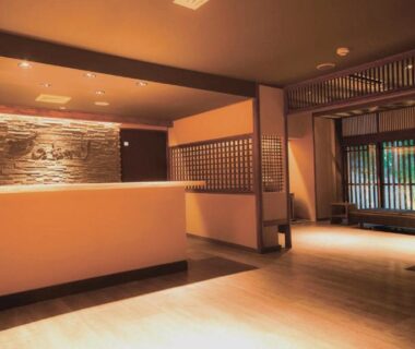 Warm lit reception desk with stone accent wall and wooden lattice screens at Tsuki no Akari in Aizu, Fukushima
