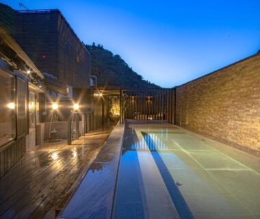 Illuminated outdoor onsen pool with wooden deck at Aizu Higashiyama Onsen Tsuki no Akari, Fukushima
