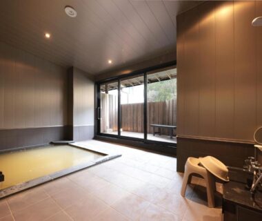 Indoor onsen bath room with wooden stool and shower at Akagi Onsen Hotel, Gunma