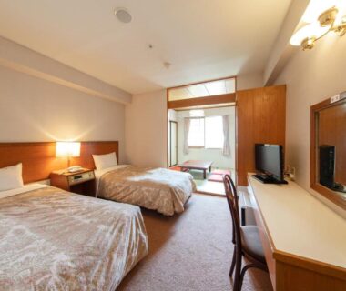 Guest room with twin beds, desk and adjoining tatami sitting area at Akakura Hotel Niigata