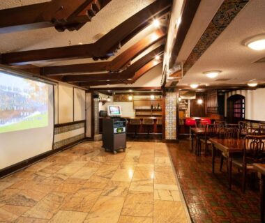 Spacious wooden-beamed lounge with projector screen and dining tables at Akakura Hotel in Chūbu, Niigata