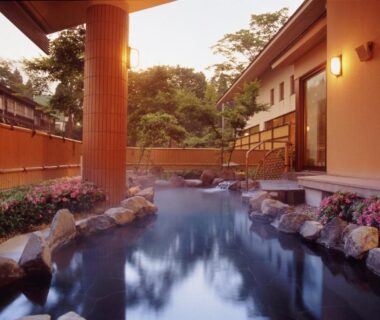 Outdoor onsen bath with stone edging and wooden pillars at Akakura Hotel in Niigata, Chūbu region