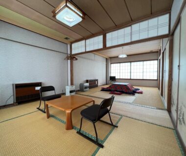 Traditional tatami room with low table, zabuton cushions, shoji screens and folded futon at Akakura Onsen Eho Ryokan, Niigata