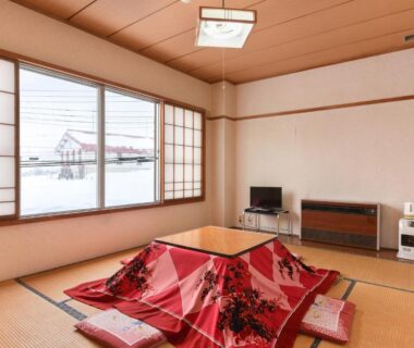 Tatami room with kotatsu, shoji screens, floor cushions and snowy window view at Akakura onsen eho ryokan, Niigata
