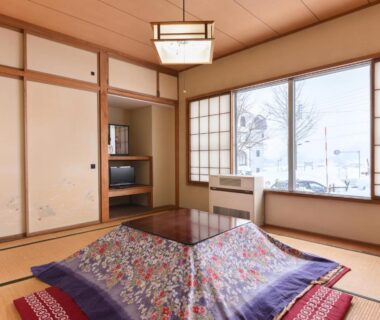 Japanese tatami room with kotatsu, shoji screens, painted fusuma and snowy view at Akakura ryokan in Niigata