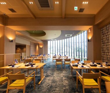 Spacious dining hall with wooden ceiling, large windows and yellow-cushioned chairs at Akarinoyado Togetsu in Oita