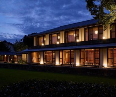 Lit two-story ryokan exterior with lawn and trees at Akazawa Geihinkan in Shizuoka, Chūbu Japan