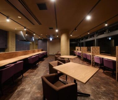 Evening lounge with partitioned seating, wooden tables and upholstered chairs at Akiu Fuga in Miyagi, Tōhoku