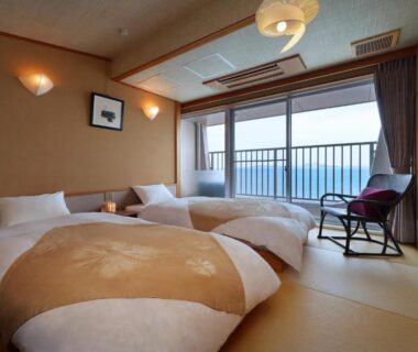 Tatami room with three low futon beds and large window overlooking the sea in Hyōgo