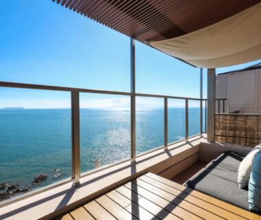 Wooden balcony with sofa and glass railing overlooking the sea at Ako Onsen Shiosaikirara Shokichi, Hyōgo