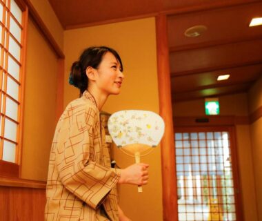 Woman in yukata holding a hand fan in wooden corridor at Ako Onsen Shiosaikirara Shokichi, Hyōgo