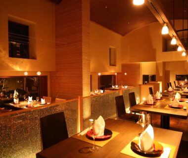 Warm-lit dining room with partitioned tables, pendant lights and folded napkins at Amahara in Hyōgo, Kansai