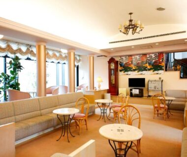 Ryokan lounge with sofas, round tables, wicker chairs and large windows at Amanohashidateso in Kyoto