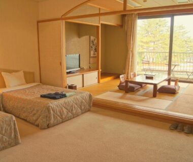 Tatami seating area with low table and twin beds at Amanohashidateso, balcony view of trees in Kyoto
