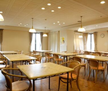 Bright dining hall with wooden tables and chairs, pendant lights at Amanohashidateso in Kyoto, Kansai, Japan