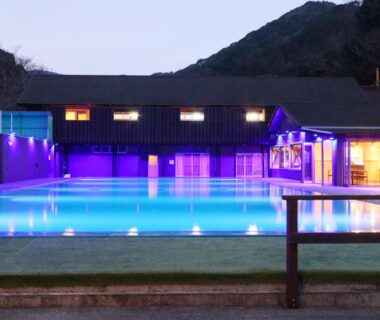 Nighttime illuminated pool and building facade at Amis Droles in Chūbu, Shizuoka