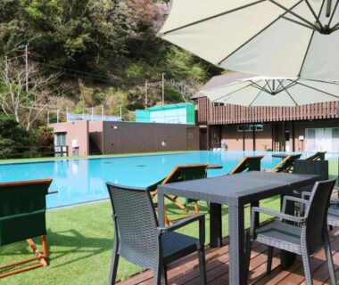 Outdoor pool with deck chairs, umbrellas and tables at Amis Droles in Shizuoka Chūbu