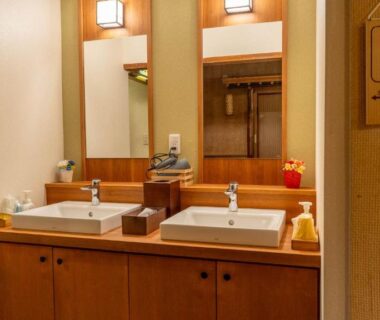 Double sink vanity with wooden cabinetry and mirrors in ryokan washroom, Andaikan, Nagano