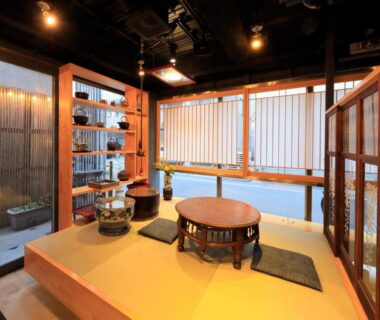 Raised tatami seating with low round table, shoji screens and wooden shelving at Andon Ryokan in Tokyo