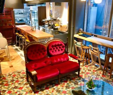 Cozy lounge with red velvet sofa, wooden bar counter, mosaic tile floor and pendant lights at Andon Ryokan Tokyo