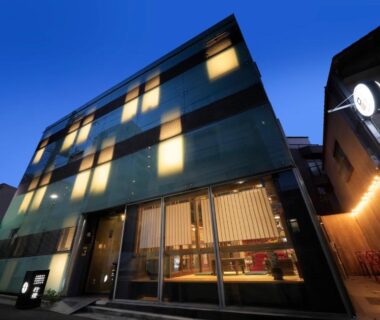 Twilight facade with illuminated windows and glass entrance at Andon Ryokan in Tokyo streetscape