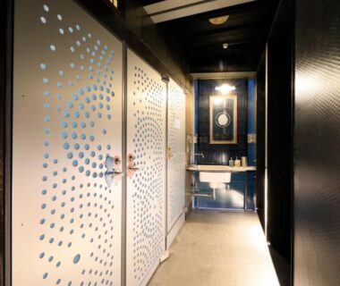 Narrow hallway with decorative perforated panels, dark wood accents, sink area, Andon Ryokan Tokyo