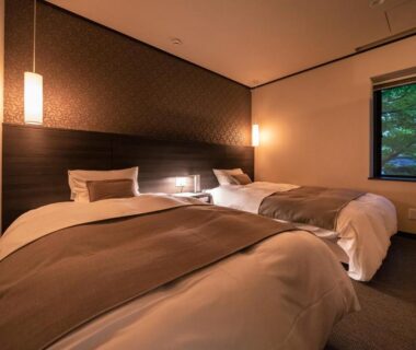 Modern twin room with bedside lamps and window showing trees at Appikogen Mori no Hotel Iwate