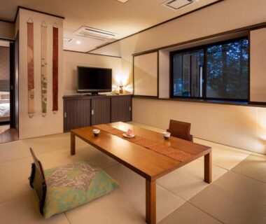 Traditional tatami room with low wooden table, floor cushions, shoji screens and adjacent bedroom at Appikogen Mori no Hotel Iwate