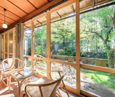 Sunlit wooden veranda with rattan chairs and garden view at Arai Ryokan, Chūbu, Shizuoka, Japan