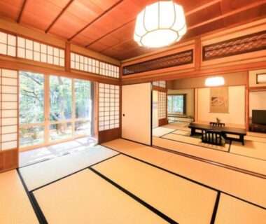 Spacious tatami room with shoji, low table and garden-facing sliding doors at Arai Ryokan in Shizuoka