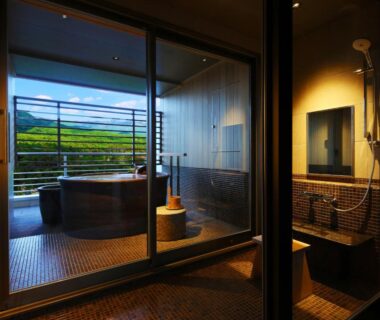 Indoor wooden soaking tub and shower with balcony and green hillside view at Arima Grand Hotel, Hyōgo