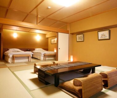 Tatami room with low table, floor cushions and two beds on raised platform at Arima Hot Spring Ryokan Hanabusubi Hyogo