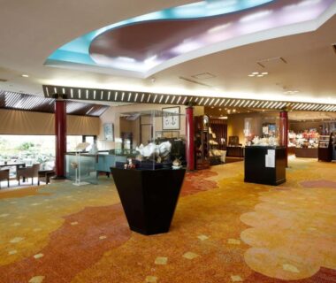Spacious ryokan lobby with decorative carpet, gift displays, seating area and illuminated ceiling at Arima Hanamusubi in Hyōgo