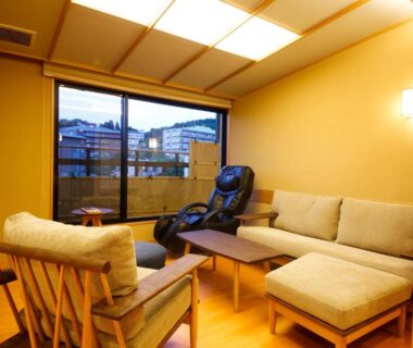 Relaxation area with sofa, armchairs, massage chair and balcony view at Arima Hot Spring Ryokan Hanamusubi in Hyōgo