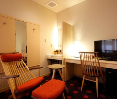 Wooden lounge chair and ottoman by desk and TV in guestroom at Arima Kotori, Hyōgo