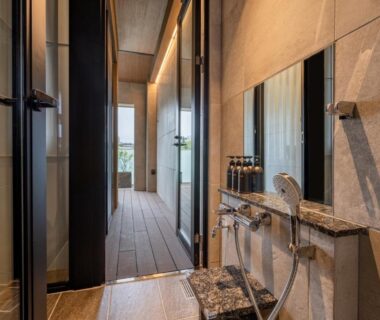 Bathing area with shower, stone vanity and wooden corridor at Arima Onsen ShikinoIrodori Hatago, Hyōgo, Japan